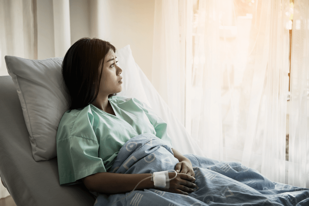 woman with unplanned pregnancy looks out the window after deciding to go through adoption after giving birth